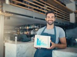 Business owner standing in shop holding an ipad.